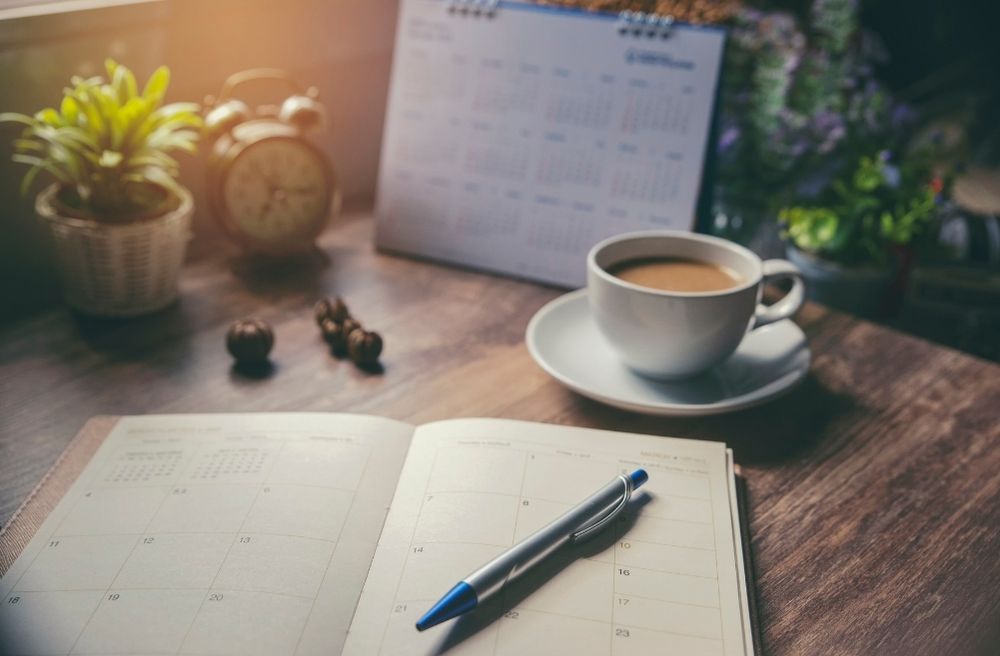 A notebook planner beside a cup of coffee