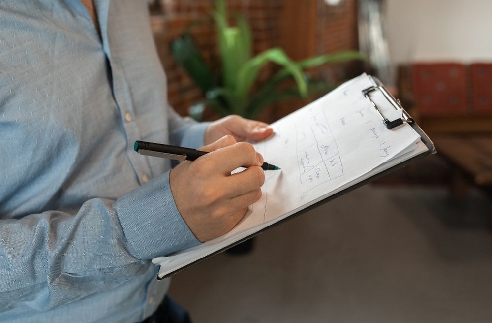 Person Holding a Black Pen Writing on a White Paper