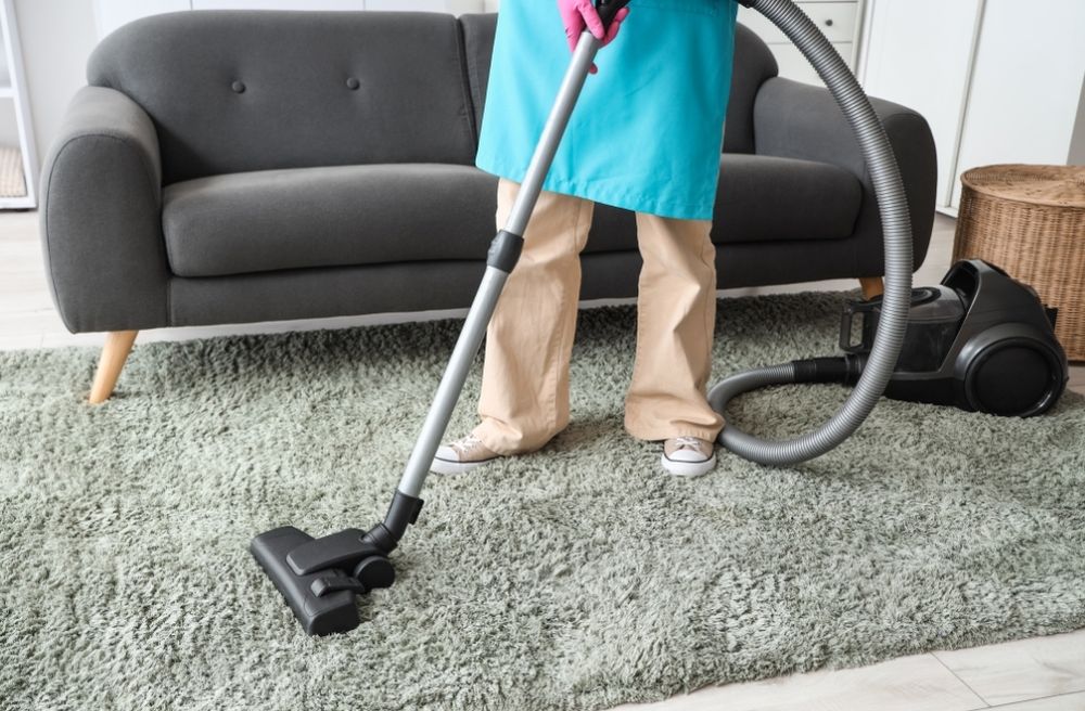 person cleaning living room before guests arrive