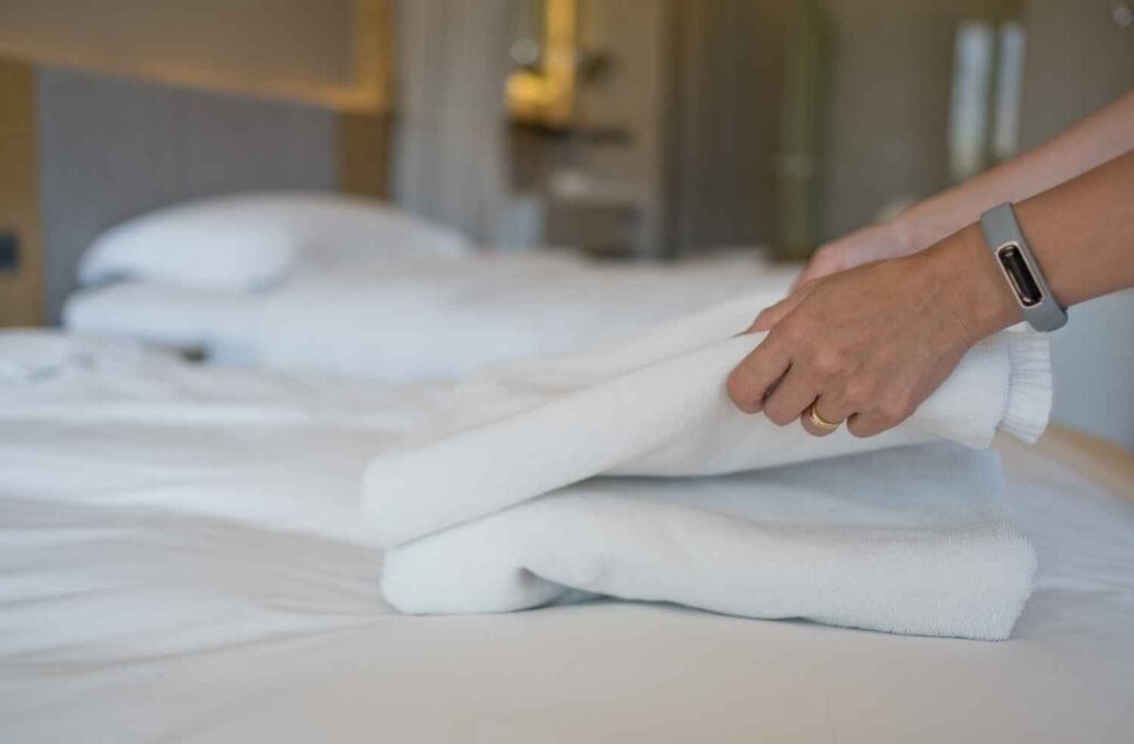 A host preparing a guest room with fresh bedding, towels, and other essentials