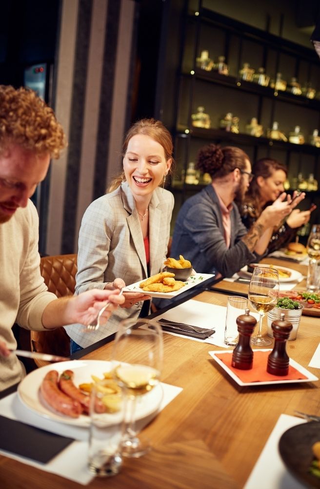 A warm dinner party scene with several guests comfortably talking and enjoying food around a dining table