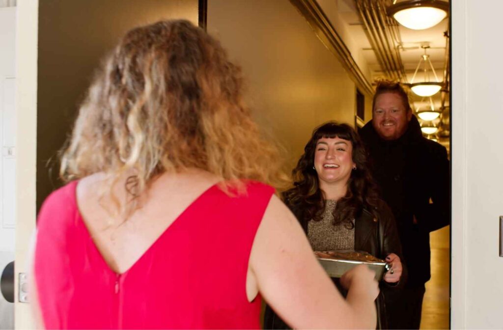A warm interaction where a host happily receives a dish from a guest