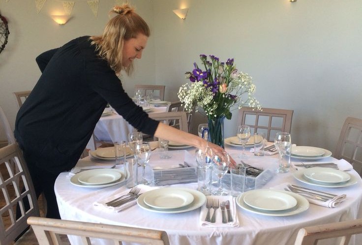A host quickly setting the table shortly before guests arrive.