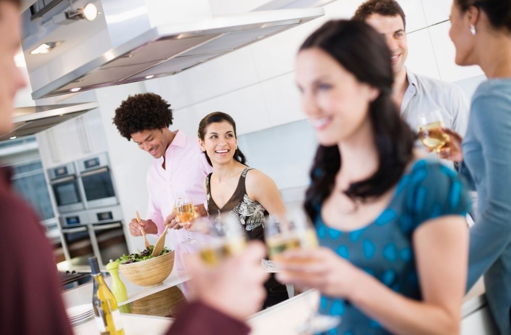 Guests standing with drinks while engaging in conversation at a home gathering